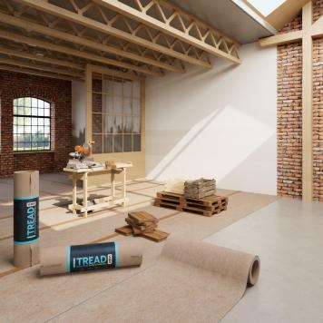 A loft style apartment with exposed brick walls and wood beams, there is brown paper on the floor and pallets